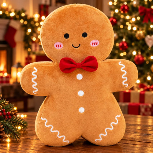 Peluche bonhomme en pain d'épices à nœud papillon rouge posée sur une table en bois devant un sapin de Noël illuminé