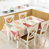 Nappe à motif sapins colorés dressée sur une table de cuisine entourée de chaises blanches