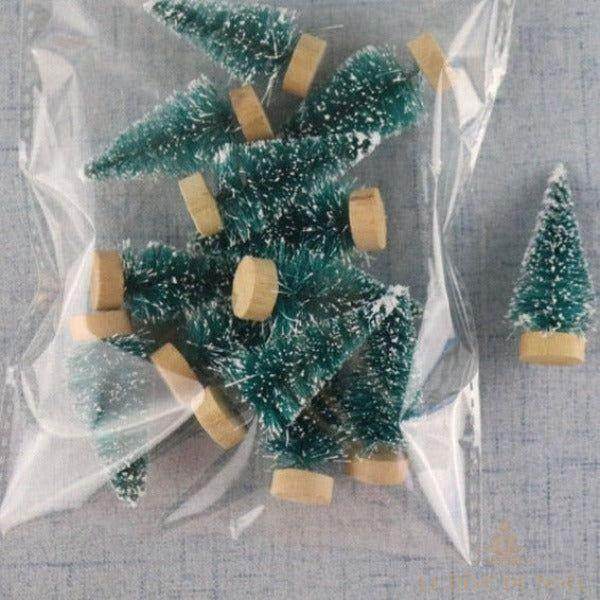 Petits sapins verts givrés à socle en bois, groupés dans un sachet plastique transparent