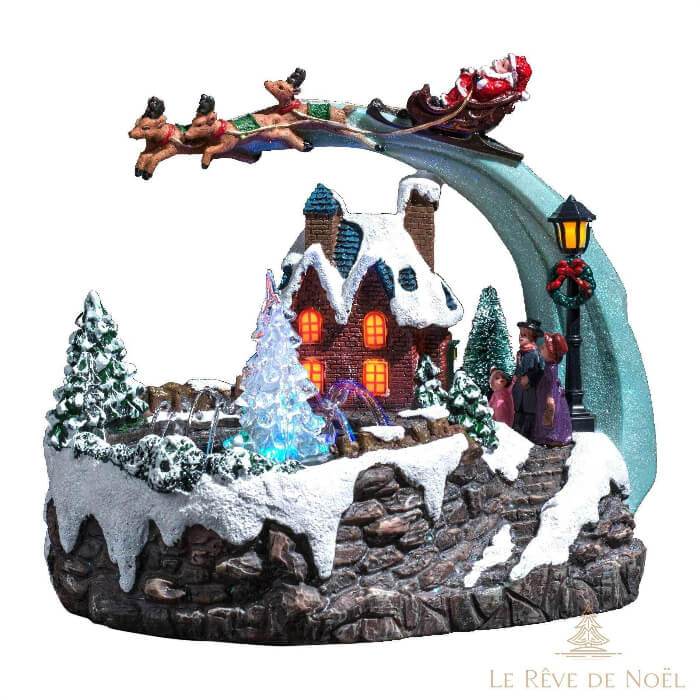Village de Noël miniature avec maison enneigée, traîneau du Père Noël en vol et sapin lumineux