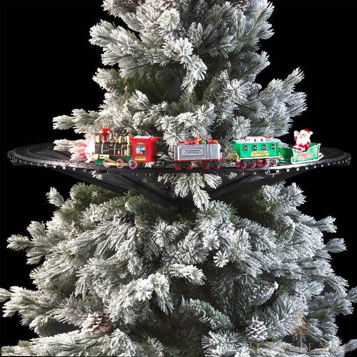 Train électrique rouge et vert circulant sur rail noir installé à mi-hauteur d'un sapin enneigé