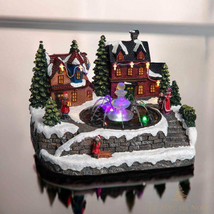 Même village lumineux de Noël photographié sur une surface brillante qui reflète le décor