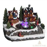 Village de Noël miniature avec maisons illuminées, sapins enneigés et fontaine à LED colorée