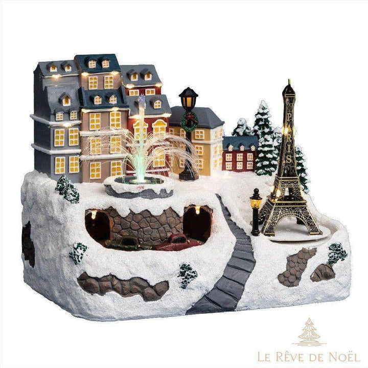 Village de Noël miniature enneigé avec tour Eiffel dorée, fontaine lumineuse et immeubles haussmanniens