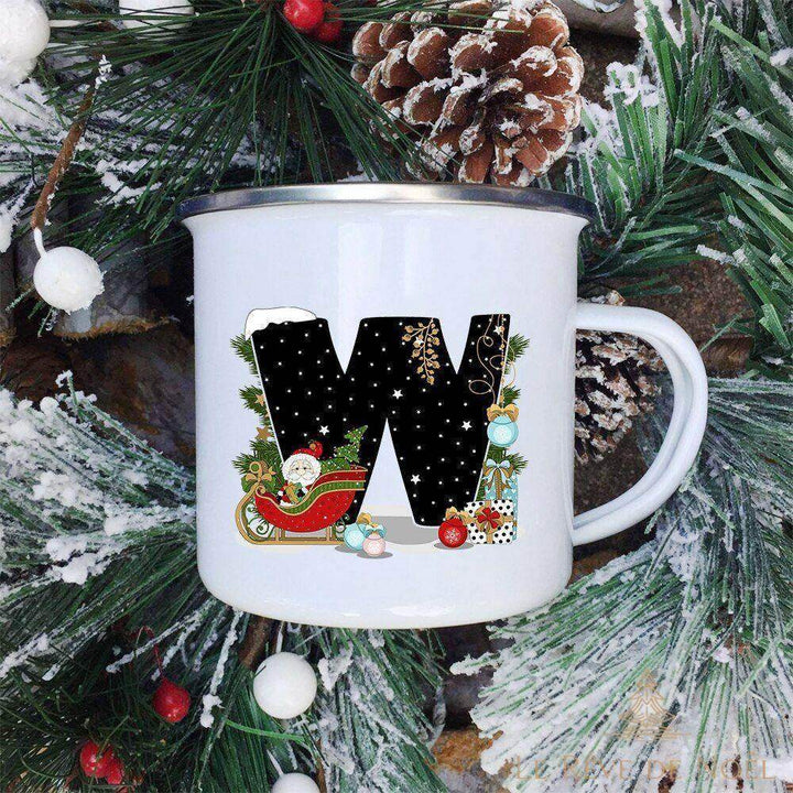 Mug lettre W illustré d'un traîneau du Père Noël chargé de cadeaux, sur fond de sapin enneigé