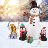 Bonhomme de neige gonflable dans un jardin enneigé le jour, une fillette joue à côté avec une pelle