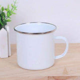 Mug émaillé blanc uni sans motif, anse assortie, posé sur une table en bois près d'une plante verte