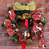 Couronne de Noël sur mur en briques, ruban rouge à motif camion tressé, gros nœud doré