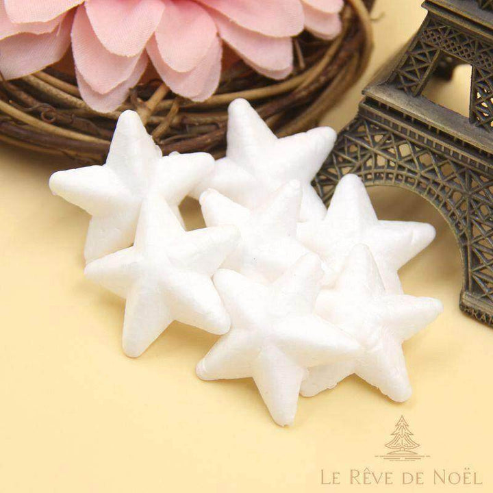 Petites étoiles blanches en polystyrène empilées, près d'une couronne de fleurs roses