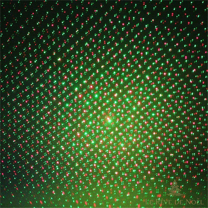 Gros plan sur les points lumineux rouges et verts projetés par le projecteur de Noël sur un mur