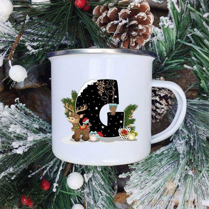 Mug émaillé blanc à lettre G noire ornée d'un renne debout et d'une pomme de pin suspendue à côté