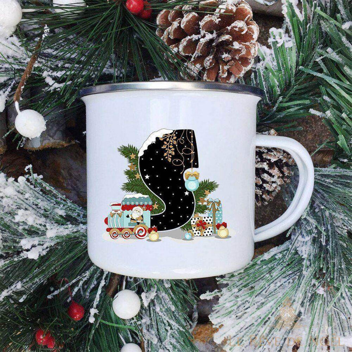 Mug blanc émaillé à lettre S noire décorée d'un petit train et du Père Noël, sur branches enneigées