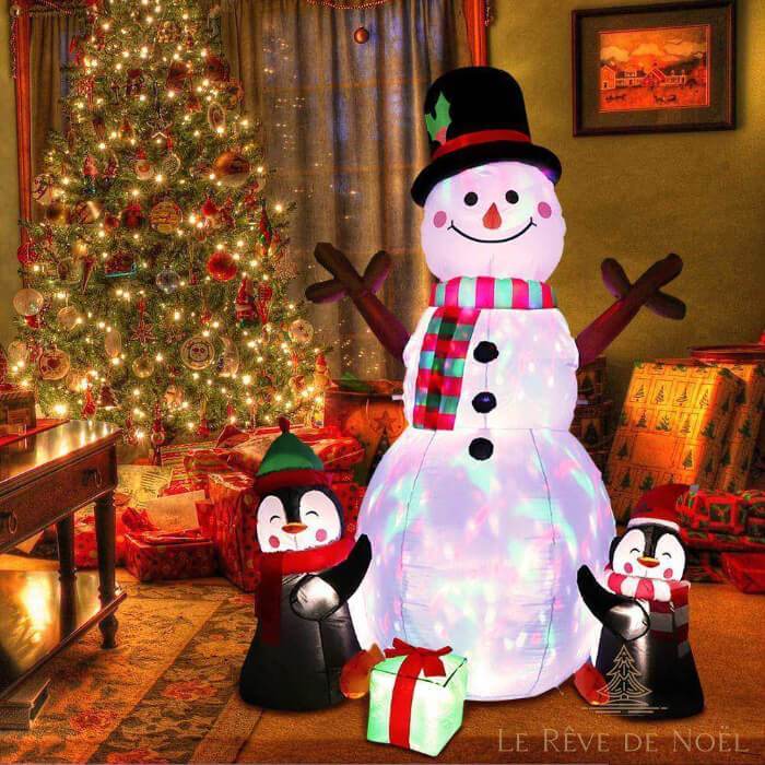 Bonhomme de neige gonflable illuminé de lumières multicolores dans un salon, près d'un sapin décoré