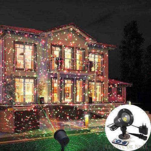 Façade de maison la nuit illuminée de points lumineux rouges et verts par le projecteur de Noël