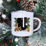 Mug émaillé blanc à lettre U noire décorée d'un faon et d'un oiseau près d'un cadeau, fond étoilé