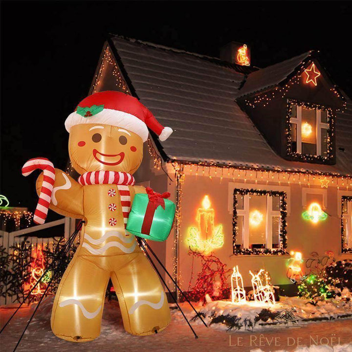 Bonhomme en pain d'épice gonflable illuminé de nuit devant une maison décorée de guirlandes
