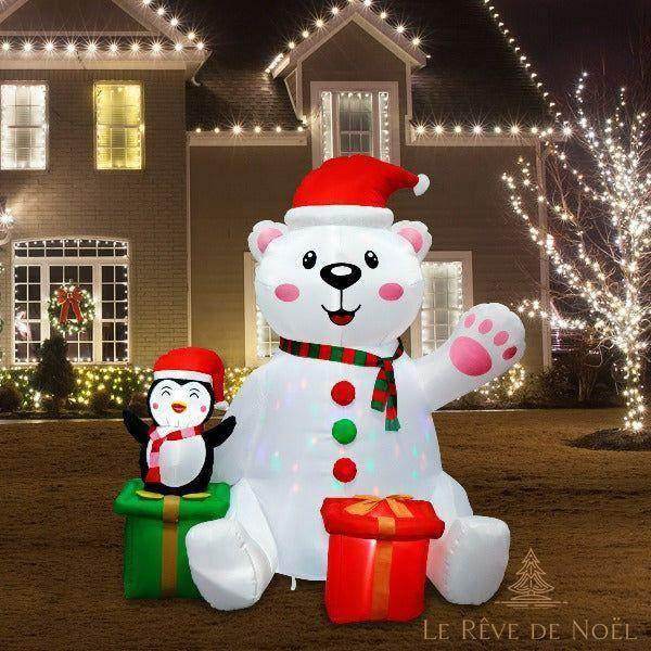Ours polaire et pingouin gonflables illuminés la nuit devant une maison ornée de guirlandes lumineuses
