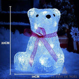 Ours en acrylique translucide illuminé de LED, ruban rose foncé noué au cou, posé dans la neige