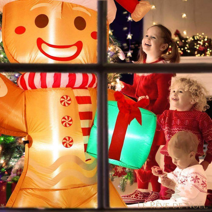 Gros plan sur un bonhomme pain d'épice gonflable lumineux, vu à travers une fenêtre avec des enfants