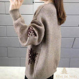 Vue de profil du pull beige, broderie de flocons de neige marron sur la manche et le flanc
