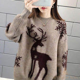 Pull beige à motif renne brodé marron, porté de face devant un mur de briques grises