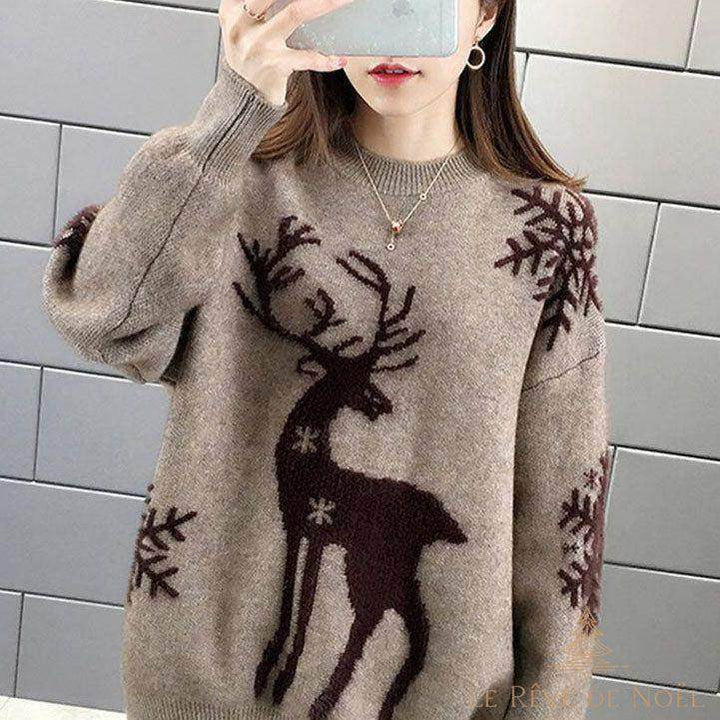 Pull beige à motif renne brodé marron, porté de face devant un mur de briques grises