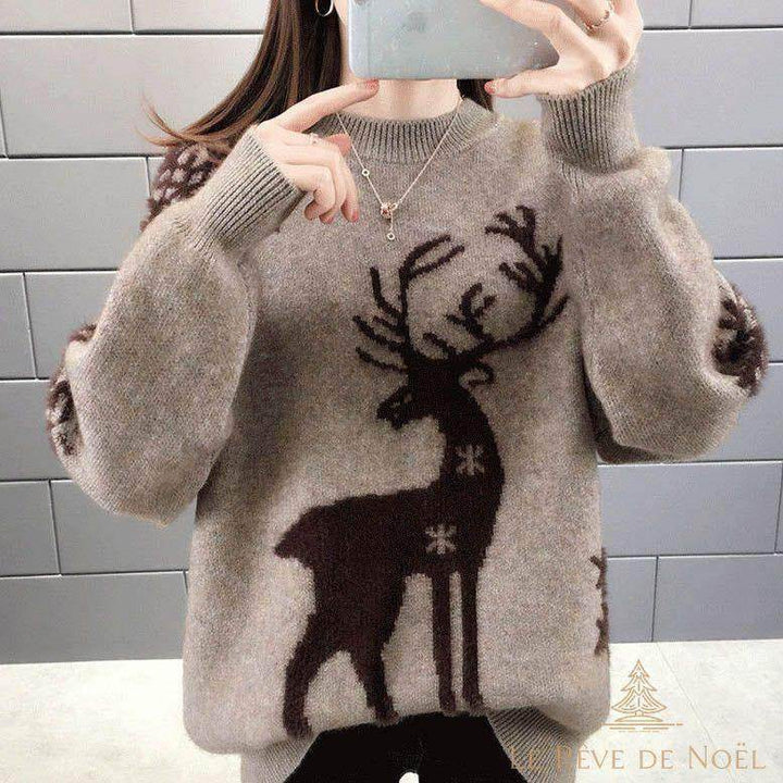Gros plan sur le motif renne brodé au centre du pull beige, porté avec un collier fin