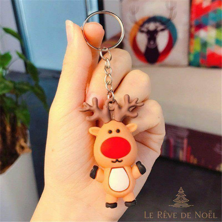 Porte-clé renne au nez rouge et bois marron, tenu entre le pouce et l'index