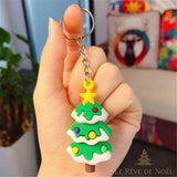 Porte-clé sapin de Noël vert avec boules colorées et étoile jaune, tenu entre les doigts