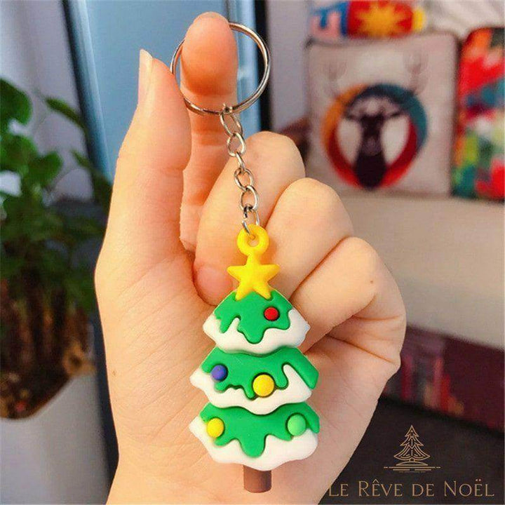 Porte-clé sapin de Noël vert avec boules colorées et étoile jaune, tenu entre les doigts