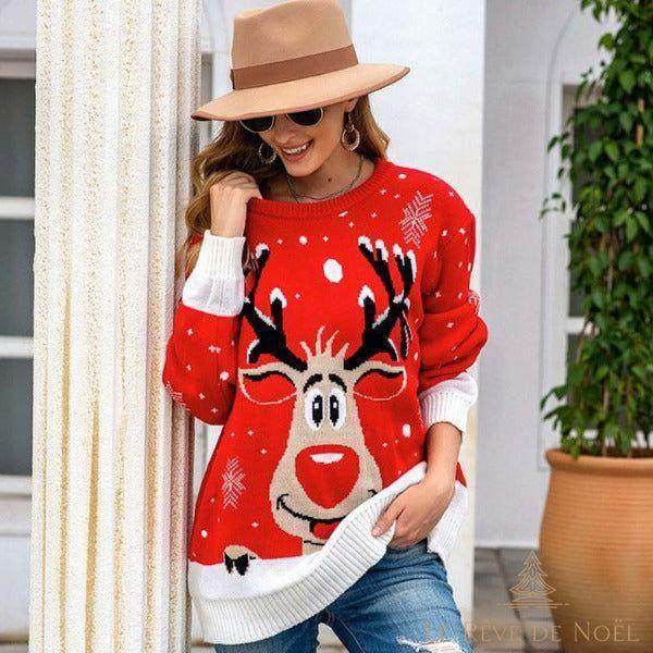 Femme portant un pull de Noël rouge et blanc à motif de renne souriant, appuyée contre une colonne