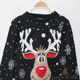 Gros plan du pull de Noël noir à motif de renne souriant et flocons, présenté sur un cintre