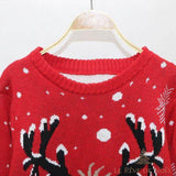 Gros plan sur l'encolure ronde d'un pull rouge, motif de bois de renne noir et flocons blancs