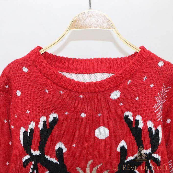 Gros plan sur l'encolure ronde d'un pull rouge, motif de bois de renne noir et flocons blancs