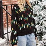 Buste du pull noir à guirlande lumineuse tricotée, porté debout près d'un sapin enneigé
