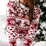Pull tricot jacquard blanc à motifs rouges cœurs, rennes et flocons, gros plan buste devant sapin