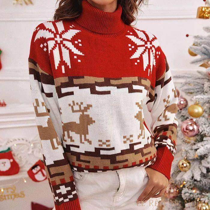 Pull de Noël femme col roulé rouge, motif de rennes marron et flocons blancs, devant un sapin