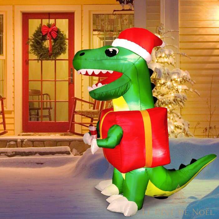 Dinosaure gonflable au crépuscule devant une maison à couronne fleurie et sapin lumineux