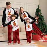 Famille en pyjama assorti motif tête de renne et carreaux rouges, jouant près du sapin