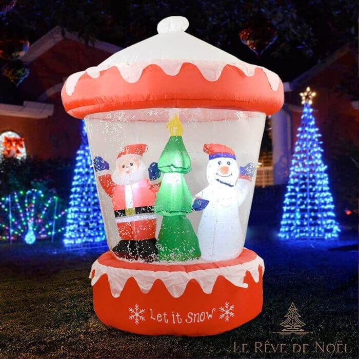 Boule à neige gonflable géante illuminée la nuit dans un jardin, Père Noël, sapin et bonhomme de neige à l'intérieur