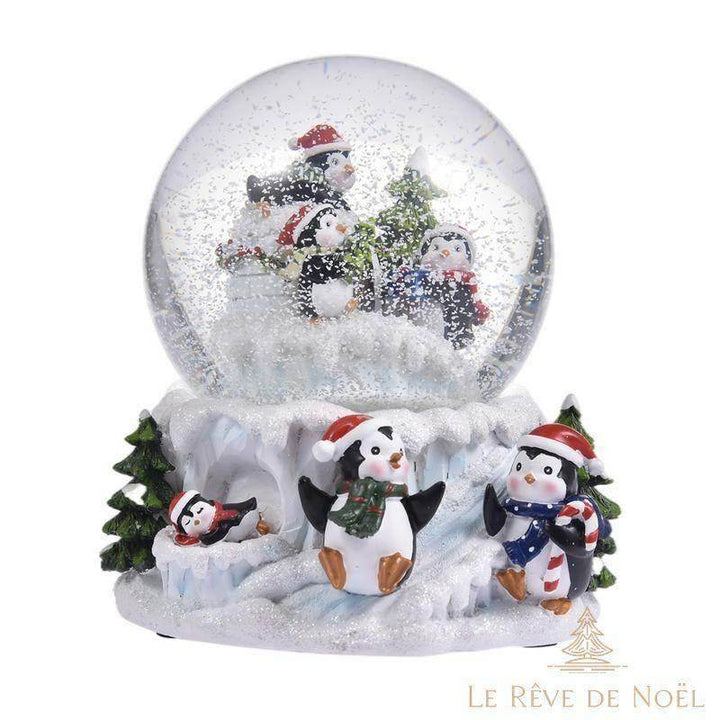 Boule à neige avec trois pingouins et un sapin dans le globe, famille de pingouins sur le socle