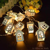 Guirlande de petites maisons lumineuses blanches empilées, barrière et fleurs jaunes en arrière-plan
