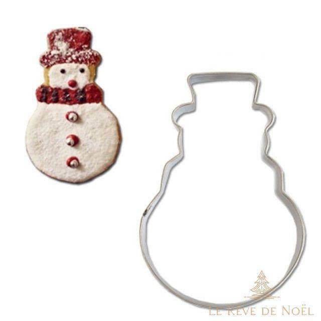 Emporte-pièce bonhomme de neige en métal, à côté d'un biscuit décoré en exemple