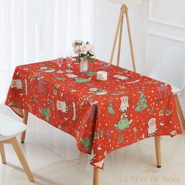 Nappe de Noël rouge à motifs Père Noël, sapins et pois dorés, dressée avec flûtes à champagne