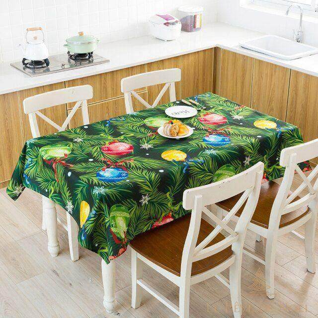 Nappe de Noël verte à motifs de boules colorées et branches de sapin, dressée dans une cuisine