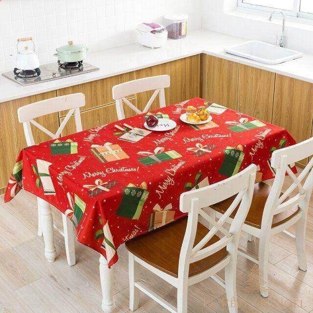 Nappe rouge à motif de cadeaux verts et inscriptions Merry Christmas, sur une table de cuisine rectangulaire