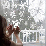 Stickers flocons de neige blancs collés sur une vitre, une fillette y pose les mains