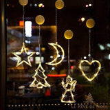 Guirlandes lumineuses en forme d'étoile, sapin, lune, ange et cœur accrochées à une vitre nocturne
