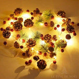 Guirlande lumineuse aux pommes de pin, baies rouges et brins de sapin allumée, disposée en cercle sur une table