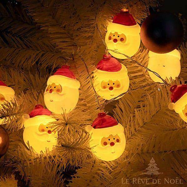 Guirlande lumineuse Père Noël accrochée à un sapin, visages lumineux à bonnet rouge
